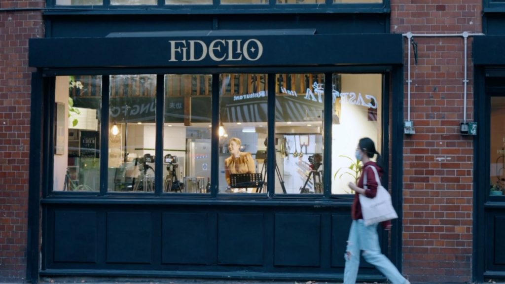 A pedestrian walks past the Fidelio Cafe while an opera singer performs inside